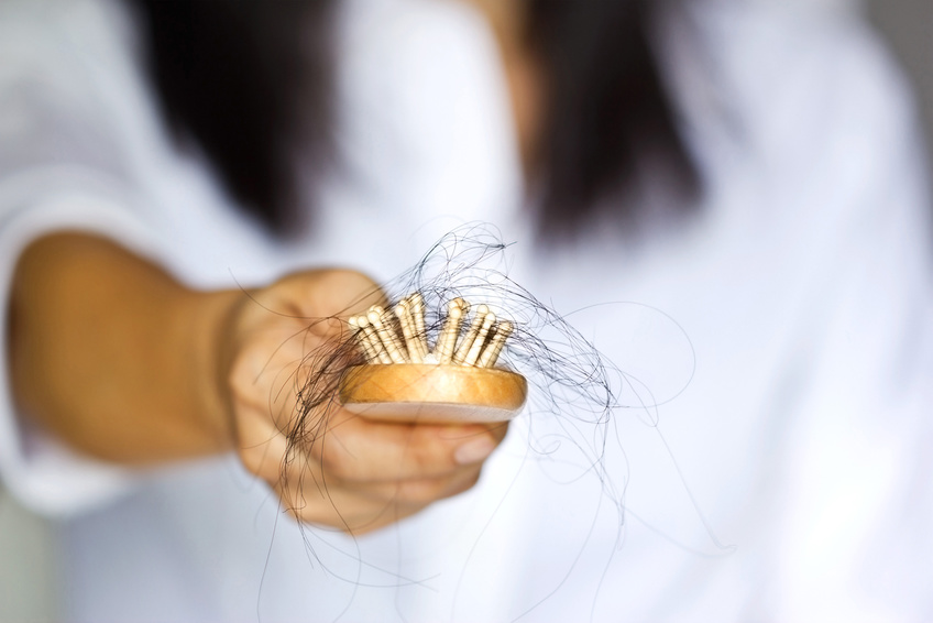 woman losing hair on hairbrush in hand, soft focus